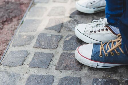Young people wearing colorful sneakers outdoor - Man and woman with canvas shoes sitting in the park...
