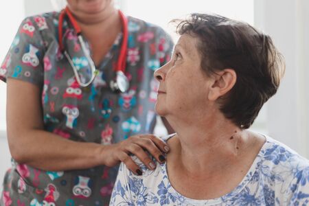 Nurse holding senior women's shoulder in the hospital - female doctor taking care and offering support to cute old lady in a private clinicの写真素材