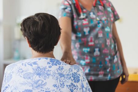 Senior woman receiving support from female nurse in the hospital - Old retired lady with health problems waiting for the doctor in the clinicの写真素材