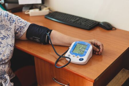 Female senior hand in blood pressure electric equipment in a hospital - Modern medical device that...