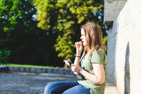 Portrait of beautiful young woman eating chocolate bar outside - Pretty girl having sweet and tasty...