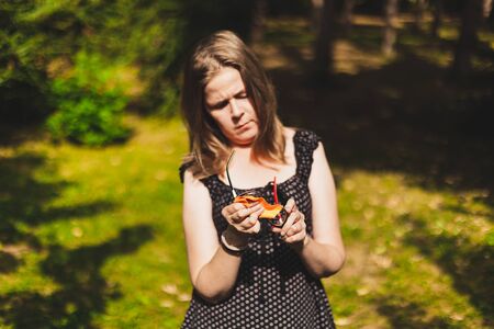 Beautiful woman with brown hair cleaning eyeglasses with smooth cloth outside - Pretty girl removing dust and dirt from her eyewear in the parkの写真素材