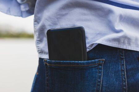 Smart phone in a rear side of pants - Back of a huge mobile telephone inside of a tight pocketの写真素材