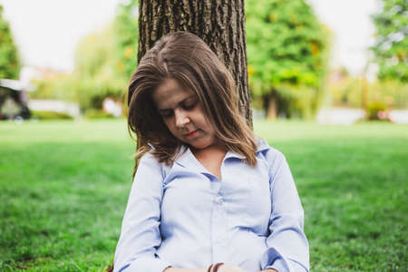 Business woman taking a nap outside in nature laying over a tree trunk - Exhausted student sleeping in campusの写真素材