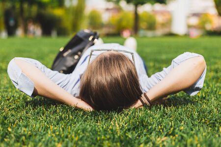 Young office lady person meditating outside in the grass - Exhausted business woman laying on the ground enjoying her piece of liberty being carefreeの写真素材