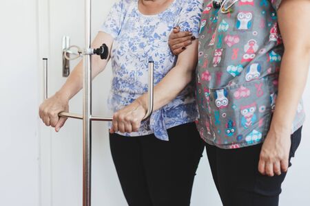 Nurse holding a senior patient that is grabbing a intravenous dropper pole - Saline fluid treatment holder for surgeryの写真素材