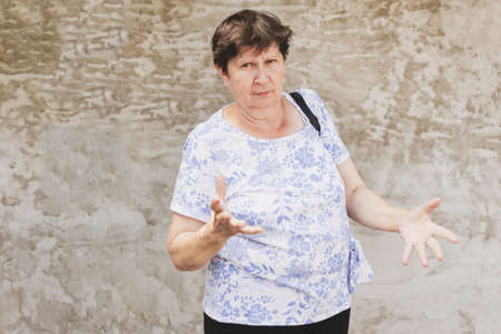 Happy senior woman portrait looking forward in the city - Smiling cute old lady standing in front of a white wall on a summer day - Elderly person enjoying life feeling carefree while walking outsideの写真素材