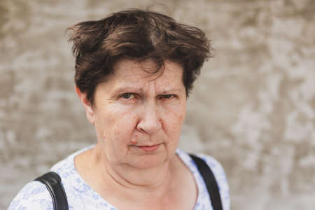 Portrait of bold senior woman looking with confidence outdoors - Cute and charismatic old lady with brown hair feeling positive and fearless while standing straight in the cityの写真素材