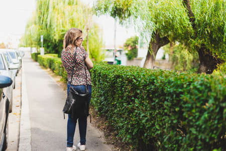 Lonely girl walking on the sidewalk admiring the view - Lonesome lady being lost and terrified outsideの写真素材