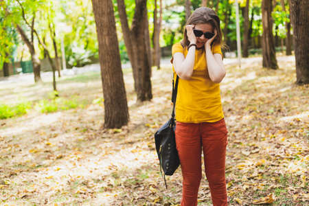 Woman with headache - Girl having a migraine outside in nature while wearing sunglasses - Young person massage herself to relief head painの写真素材