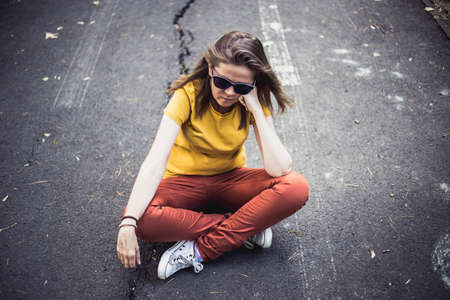 Woman sitting with crossed legs while looking down - Loneliness - Lonely girl - Peaceful person thinking outsideの写真素材