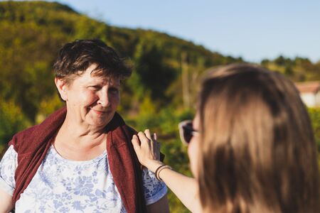 Portrait of mother and daughter talking while walking in nature on a summer day - Two happy smiling females having fun and feeling good in vacation - Concept image for family and lifestyleの写真素材