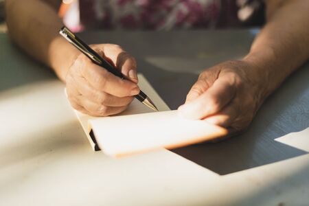 Woman taking notes - Close-up to female hands holding a pen and a notebook - Journalist writing at...