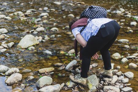 Senior woman having fun playing near a river in nature on a summer day â Pretty old lady feeling good outdoors hiking in the woodsの写真素材