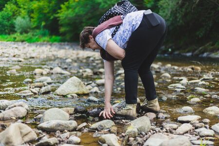 Happy senior woman hiking on a summer day - Cute old lady relaxing and feeling good while playing near a river - Elderly person enjoying light activity outsideの写真素材