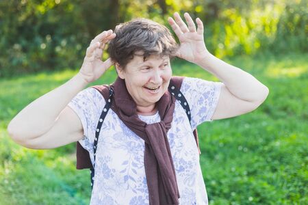 Happy senior woman having fun and feeling good outside - Beautiful old lady relaxing in nature while acting silly on a bright summer day - Elderly person having a balanced and joyful lifestyleの写真素材