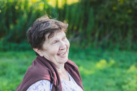 Portrait of beautiful senior woman laughing in nature - Happy smiling old lady daydreaming on a summer day outside - Elderly person enjoying life feeling carefree and relaxedの写真素材