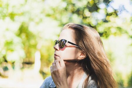 Playful woman twirling hair while wearing sunglasses - Pretty girl being seductive while playing with her strand outsideの写真素材