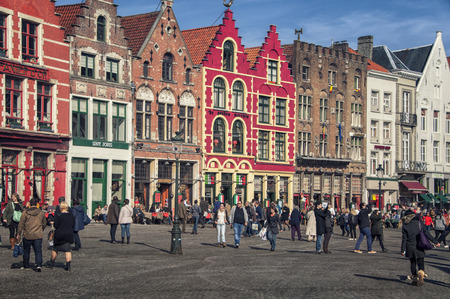 BRUGES, BELGIUM - MARCH 8, 2014: Tourists in front of famous old colorful buildings at Market square. Popular Flemish city with almost intact medieval architecture.のeditorial素材