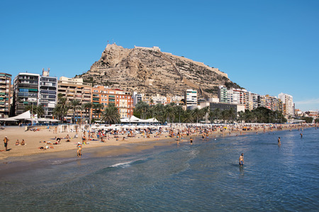 ALICANTE, SPAIN - OCTOBER 24, 2014: Crowded city beach with Santa Barbara Castle located on Mount Benacantil. Famous Costa Blanca touristic resort, mediterranean sea.のeditorial素材