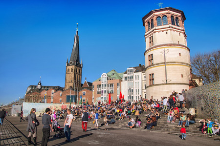 DUSSELDORF, GERMANY - MARCH 20, 2014: Crowd of people sitting at the steps in front of Schlossturm in Altstadt in the sunny spring day.のeditorial素材