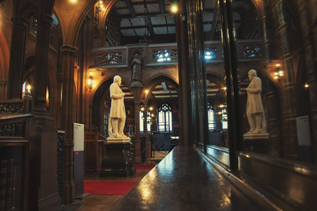 MANCHESTER, UK - SEPTEMBER 3, 2014: Inside a John Rylands Library - a late-Victorian neo-Gothic building and a famous landmark. Interior decoration of a reading room with a statue and bookshelvesのeditorial素材