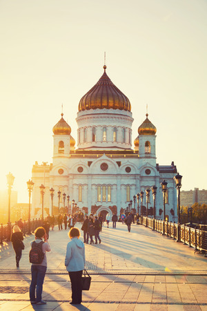 MOSCOW, RUSSIA - MAY 5, 2015: Sun sinking behind the Cathedral of Christ the Savior. Sunlight over Patriarshiy Bridge with people walking, taking photos, watchingのeditorial素材