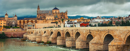 CORDOBA, SPAIN - OCTOBER 10, 2014: Roman bridge across the Guadalquivir river and La Mesquita Cathedral with people walking around sightseeing. Popular touristic place, toning effectのeditorial素材