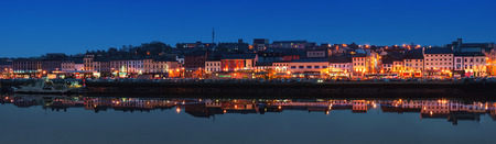 WATERFORD, IRELAND - NOVEMBER 29, 2014: Panoramic view of a cityscape at night with illumination. It is the oldest city in the country where located many restaurants, shops, bars. Moored ship.のeditorial素材