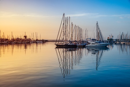 Sunrise over the Alicante harbor, Costa Blanca, Spain - popular mediterranean summer resort with luxury yachts. Reflection in the waterの写真素材