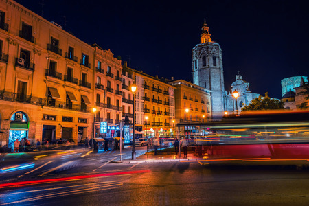 Illuminated historical buildings at the Reina square in Valencia, Spain. Night view of motion blurred cars and buses. Light trailsの写真素材