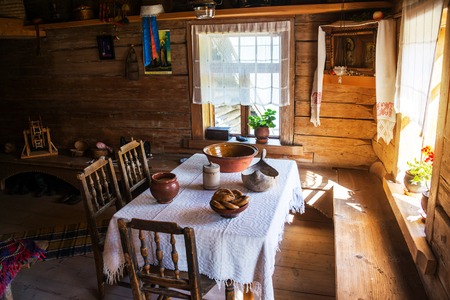 VELIKY NOVGOROD, RUSSIA - AUGUST 10, 2015: Inside a typical wooden house - table with chairs and two sun lighted windows. Museum of wooden architecture called Vitoslavlitsyのeditorial素材