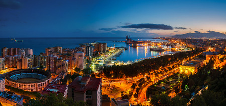 Malaga, Spain. Aerial view of City Hall, port and Bullring arena with illuminated buildings and Mediterranean sea in Malaga, Andalusia, Spain at night with sunset skyの写真素材