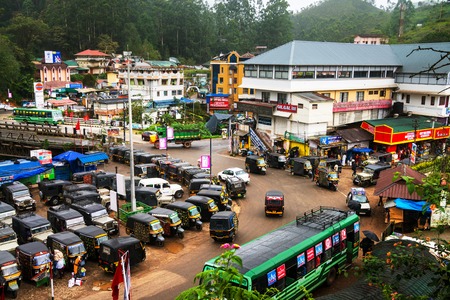 MUNNAR, INDIA - JUNE 24, 2016: Crowded junction in the mountain village Munnar located in Kerala, India. Tuk-tuk and buses traffic with people during the heavy rainのeditorial素材