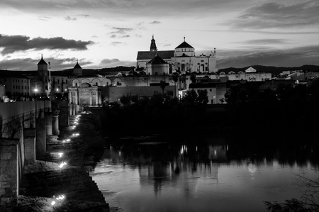 Cordoba, Spain. Illuminated Roman bridge and La Mezquita at sunset in Cordoba, Andalusia, Spain. Guadalquivir river. Black and whiteの写真素材