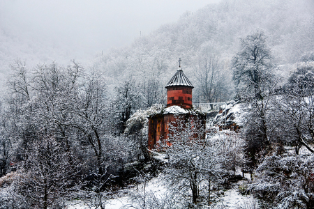 Beautiful church in Armenia covered in snow with forest in winterの写真素材