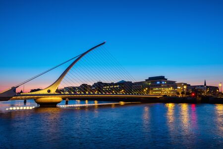 Dublin, Ireland. Samuel Becket Bridge at sunset in Dublin, Ireland. Beautiful architecture and illuminated hotels with reflection in the waterの写真素材