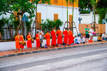 LUANG PRABANG, LAOS - JULY 27, 2016: Alms giving in the morning when monks walk by the streets for the food. Young monks in Luang Prabang, Laosのeditorial素材