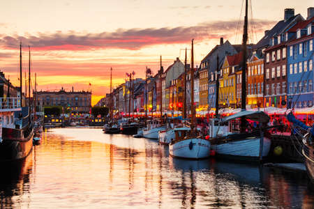 COPENHAGEN, DENMARK - AUGUST 12, 2019: View of famous Nyhavn area in the center of Copenhagen, Denmark at night. Various boats moored with historical buildings and cloudy sunset skyのeditorial素材