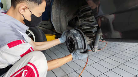 An Indonesian car mechanic is checking Rear brake of a car in an authorized workshop dealerの写真素材