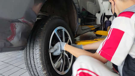 A car mechanic is installing a wheel on a carの写真素材