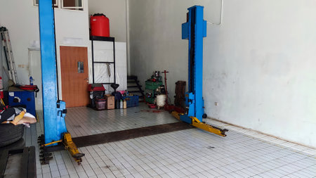 An Indonesian authorized workshop with on big blue four post car lift and some tools and white air compressorの写真素材