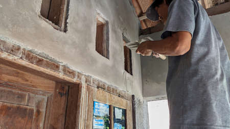 an Old Indonesian house builder is making a frame for ventilation holes in a houseの写真素材