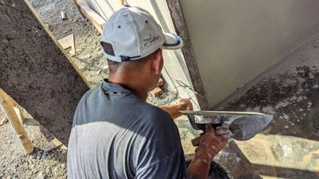 An old male Indonesian builder is checking the flatness of a wall edge using traditional toolsの写真素材