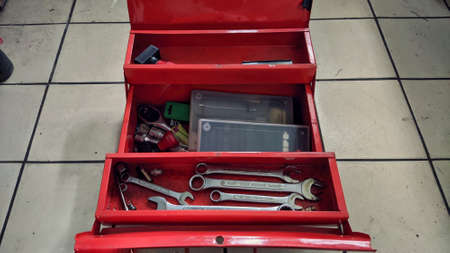 A small red Technician tool box which contain several wrenches of various sizes and stamp is on the...