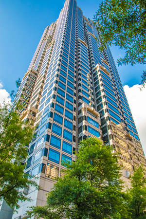 Atlanta, Ga / USA - 05 30 20: Tall shiny skyscraper downtown with trees and blue sky