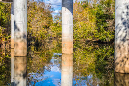 Bridge columns reflection in a calm river in the Fall in the south