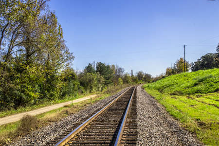 View of train tracks fading into the distance and green grass and blue skies
