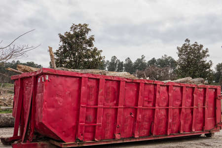 Augusta, Ga USA - 03 17 21: Urban scene a red open top dumpster filled with logs