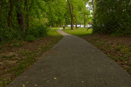 A concrete walking trail in a nature park and river in distance rural Georgia